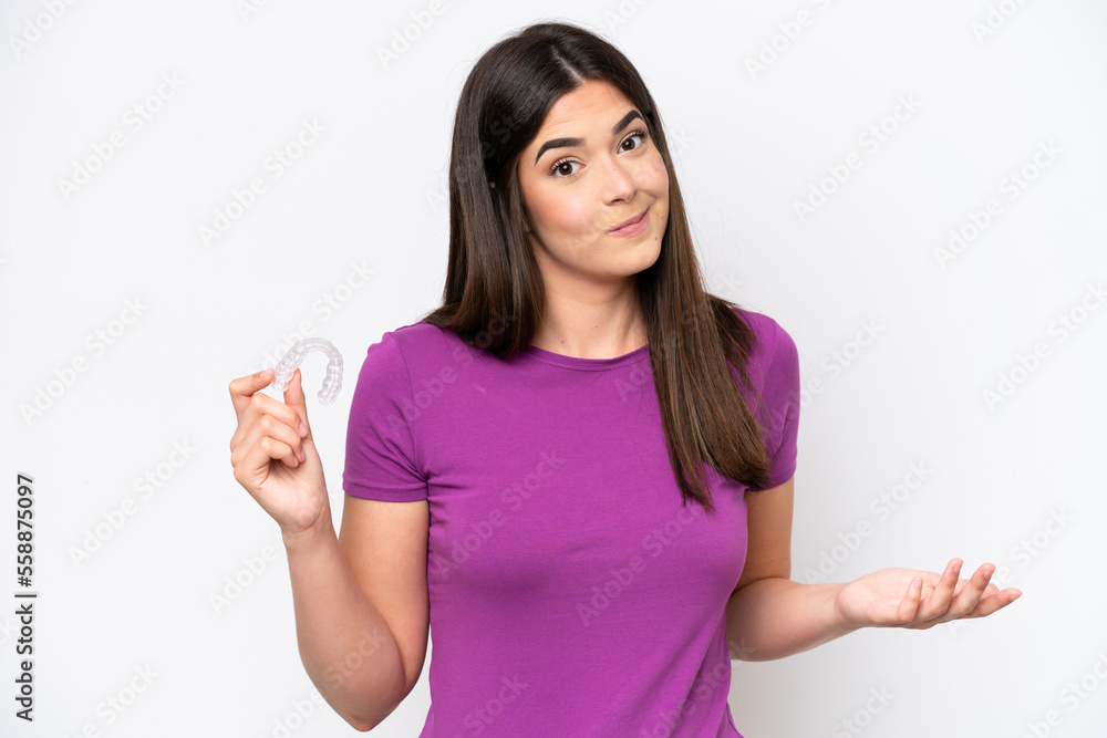 Young Brazilian woman holding invisible braces isolated on white background making doubts gesture while lifting the shoulders Young Brazilian woman holding invisible braces isolated on white background making doubts gesture while lifting the shoulders