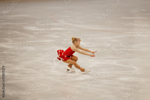 a little girl in a red dress participates in a figure skating competition 