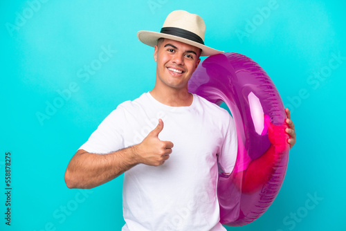Bild auf Leinwand Young caucasian man holding air mattress isolated on blue background with thumbs