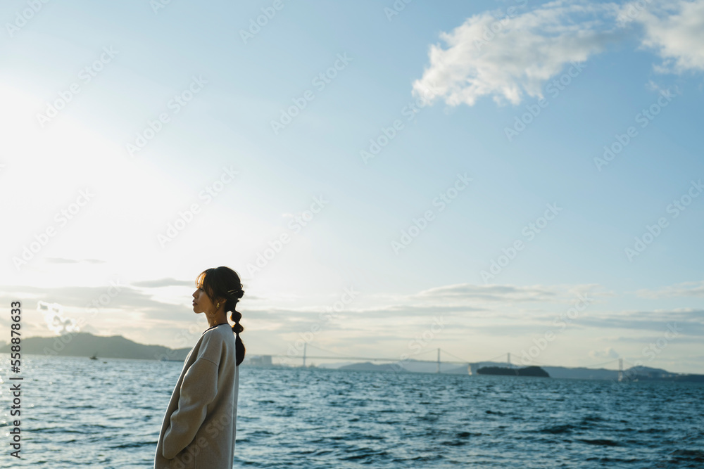 海で夕日を見ている女性 海で夕日を見ている女性