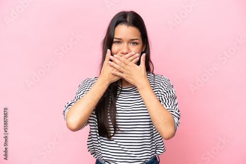 Young Colombian woman isolated on pink background covering mouth with hands