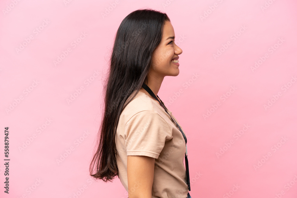 Young Colombian woman with a motorcycle helmet isolated on white background laughing in lateral position Young Colombian woman with a motorcycle helmet isolated on white background laughing in lateral position