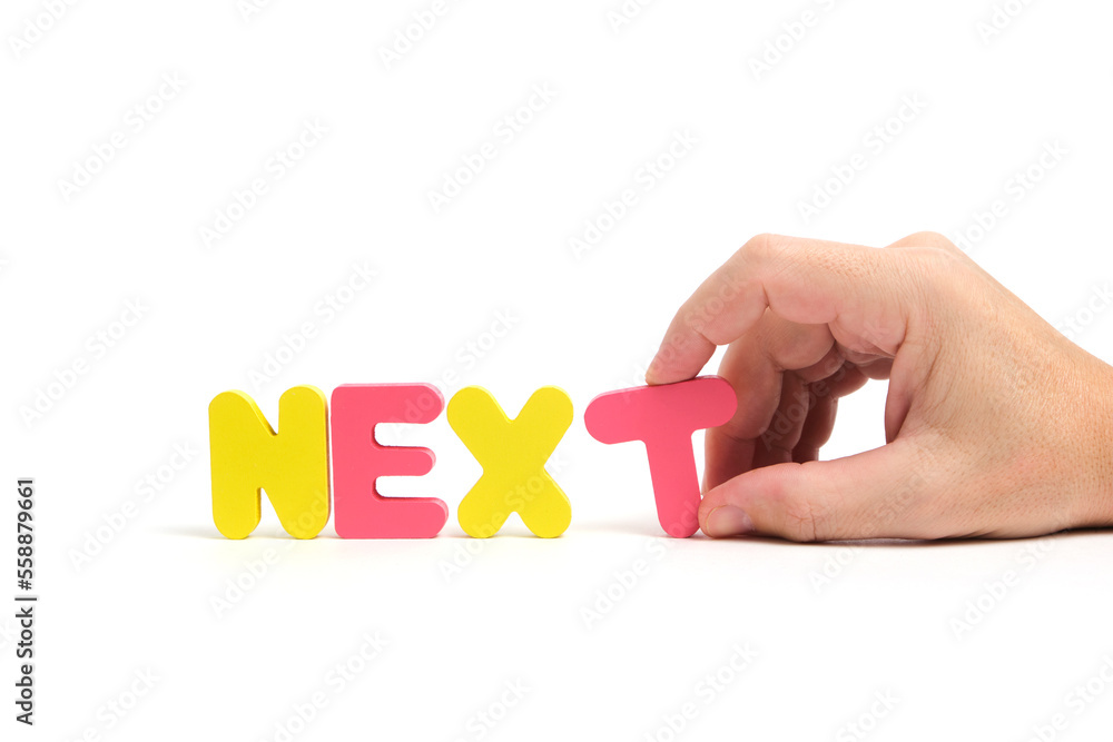 Man hand composes the word next in letters on white background.