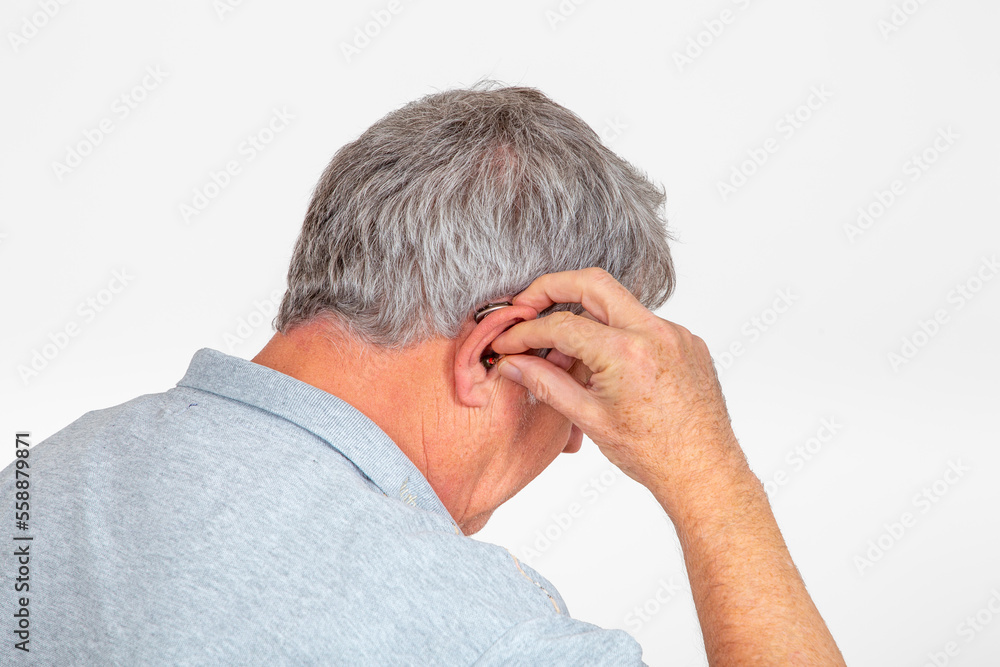 portrait of caucasian man putting the hearing aid in the ear portrait of caucasian man putting the hearing aid in the ear
