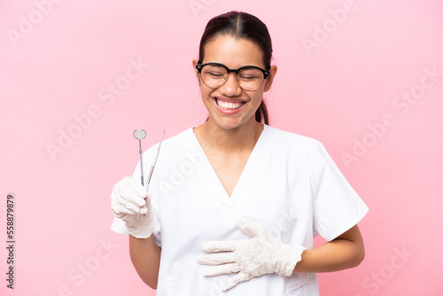 Dentist Colombian woman isolated on pink background smiling a lot