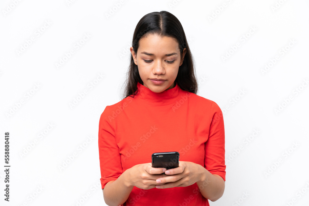Young Colombian woman isolated on white background using mobile phone Young Colombian woman isolated on white background using mobile phone