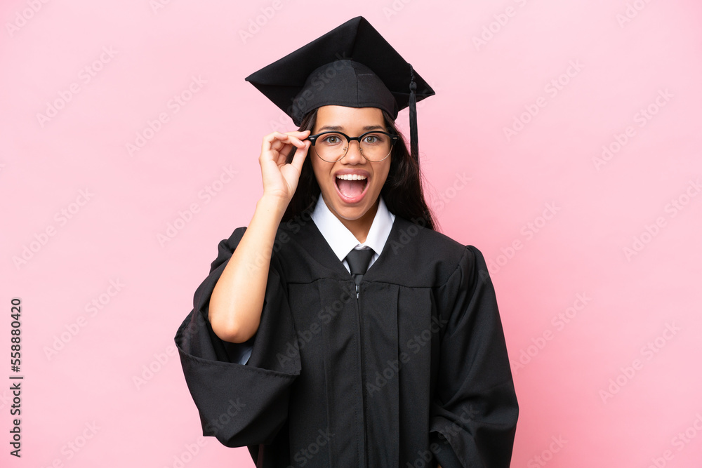 Young university Colombian woman graduate isolated on pink background with glasses and surprised Young university Colombian woman graduate isolated on pink background with glasses and surprised