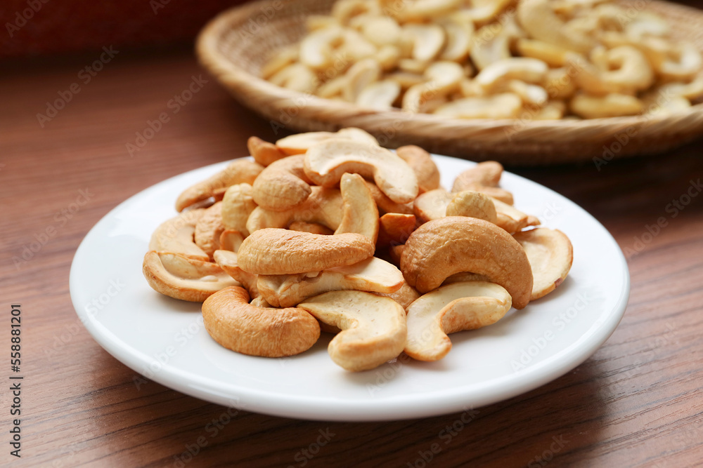 A Plate of Delectable Roasted Cashew Nuts with the Uncooked in Backdrop A Plate of Delectable Roasted Cashew Nuts with the Uncooked in Backdrop