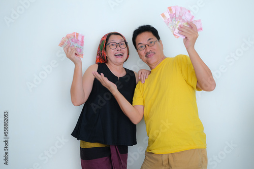 Husband and wife standing, looking happy with lots of cash money in their hands photo
