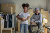 Confident mixed race young couple of Asian man and African-American woman retail seller, entrepreneur, online store drop shipping small business owner looking at camera in delivery shipping warehouse