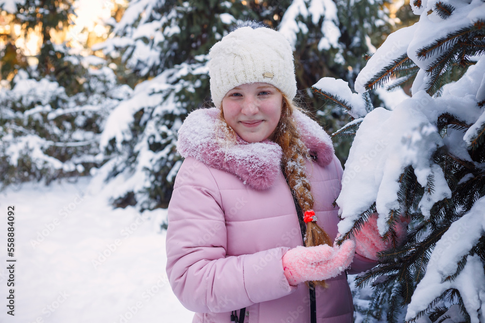 Obraz premium a girl stands near a snowy Christmas tree in winter and throws up snow
