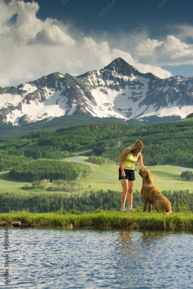 A woman petting her dog below Mount Wilson, Telluride, Colorado. A woman petting her dog below Mount Wilson, Telluride, Colorado.