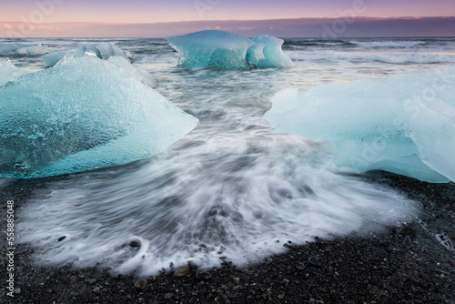 Glacial ice from BreiÃ°amerkurjÃ¶kull sits on the beach  of the coast at BreiÃ°amerkursandur, Iceland, also known as the Jokulsarlon. photo