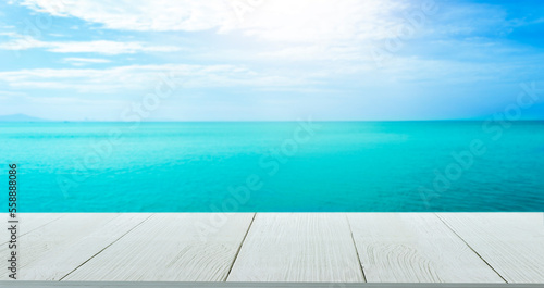 Beautiful wooden floor and blue background, sea water and sky. © watchara