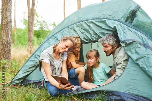 Woman showing digital tablet to family in tent