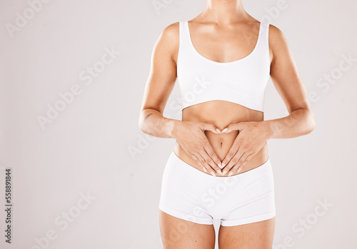 Health, body and hands in heart of a woman with lose weight results, fitness and beauty goals on studio white background. Underwear, skincare and model woman with gut health, stomach and diet mockup