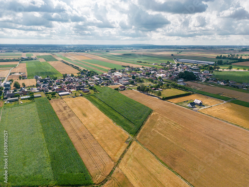 pola i łąki z miedzami i wioską z lotu ptaka