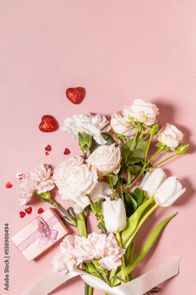 Valentine's Day greeting card with beautiful flowers and gift on pink background. Valentine's day, Womans day, wedding, birthday or mothers day. View from above. Copy space.