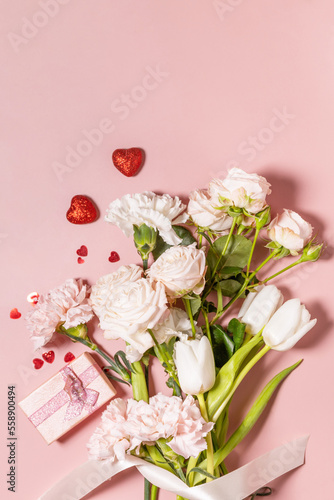 Fototapeta Naklejka Na Ścianę i Meble -  Valentine's Day greeting card with beautiful flowers and gift on pink background. Valentine's day, Womans day, wedding, birthday or mothers day. View from above. Copy space.