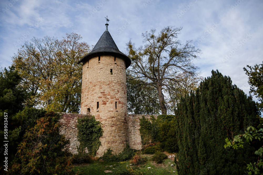 Wernigerode, Saxony-Anhalt, Germany, 29 October 2022: Ancient stone defensive town wall tower and moat, narrow slit windows, sunny autumn day, historic center in medieval city, historical buildings