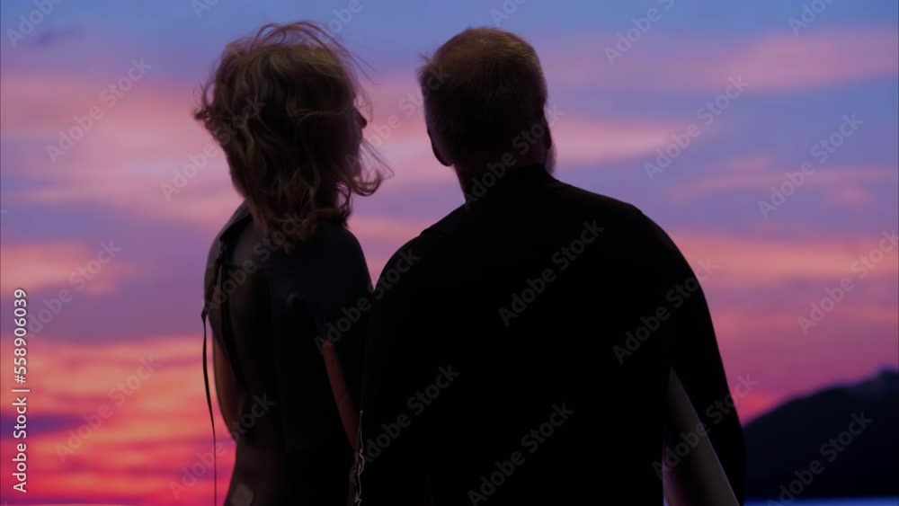 Portrait of mature adult 60s Caucasian surfers couple enjoying the view of beautiful sunset over the ocean Portrait of mature adult 60s Caucasian surfers couple enjoying the view of beautiful sunset over the ocean