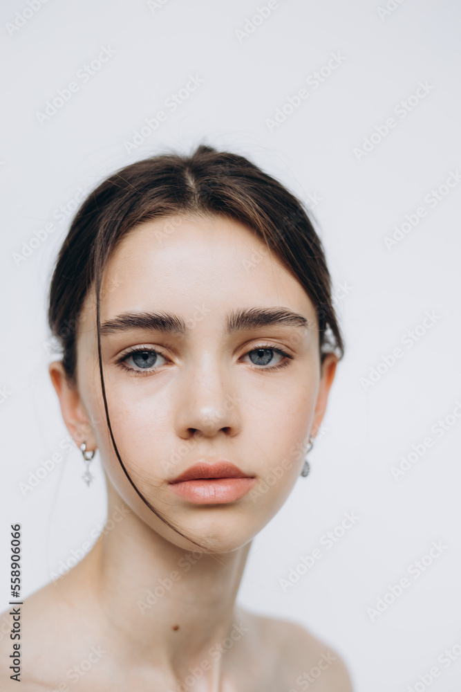 stylish portrait of a young 15-year-old model girl with natural light in a spacious photo studio