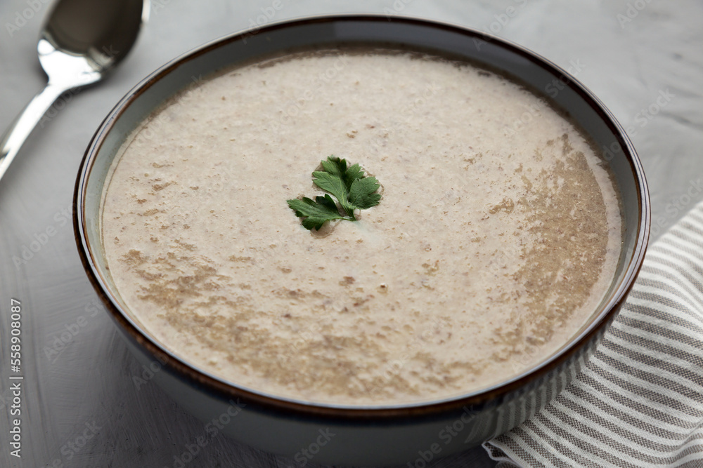 Homemade Cream of Mushroom Soup in a Bowl on a gray background, side view. Close-up. Homemade Cream of Mushroom Soup in a Bowl on a gray background, side view. Close-up.