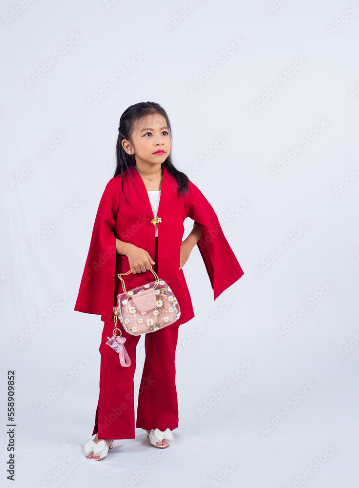 A portrait of a little asian girl wearing red dress, two hands holding a fashion handbag isolated on white background. 
