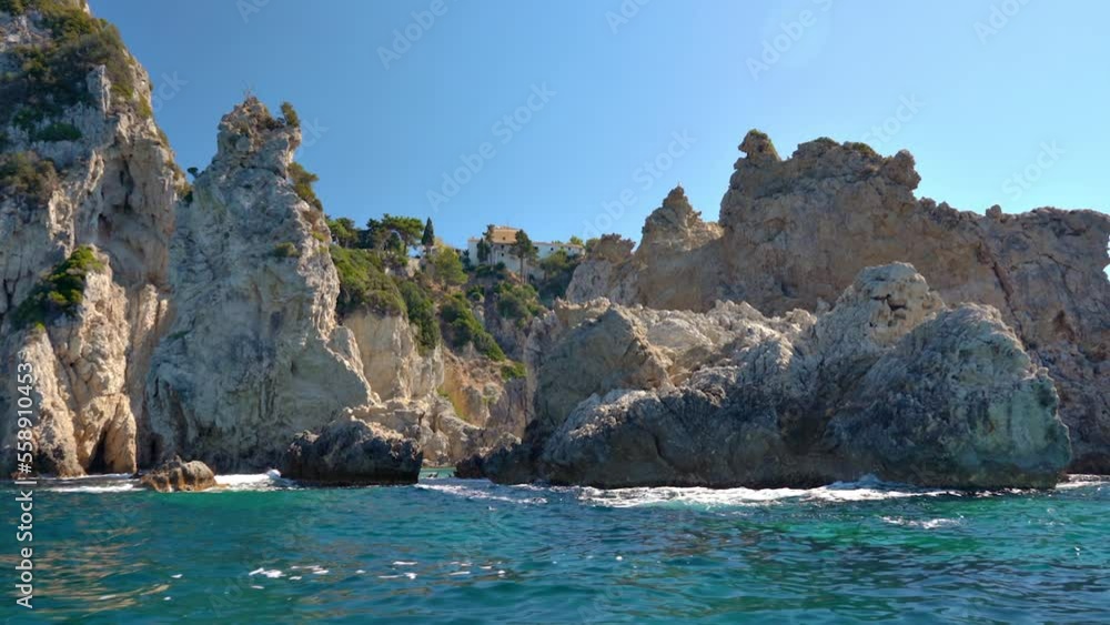 Sharp tall rocky cliffs visible above water - typical seascape near Paleokastritsa, Corfu Greece, view from a boat, monastery can be seen on top of mountain background Sharp tall rocky cliffs visible above water - typical seascape near Paleokastritsa, Corfu Greece, view from a boat, monastery can be seen on top of mountain background