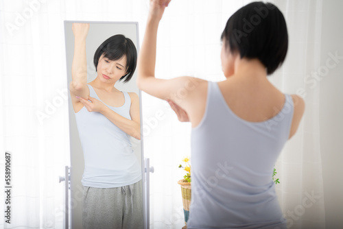 鏡で二の腕をチェックしている若い女性 ダイエットイメージ 