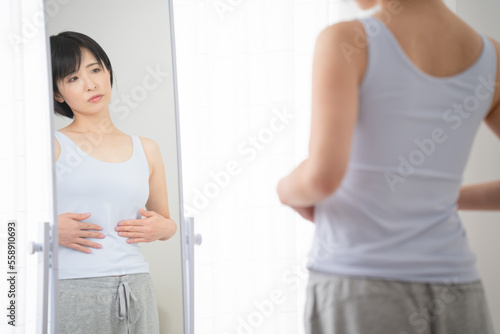 鏡でウェストをチェックする若い女性 ダイエットイメージ