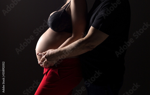 Silhouette of a pregnant woman on a black background. A pregnant couple. A pregnant belly. Pregnant woman holding her belly.