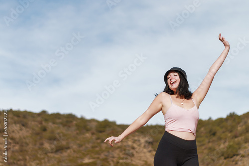 young woman standing arms open happy and dancing for being in nature