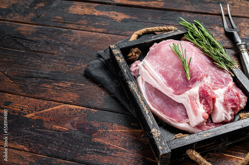 Fotografie, Obraz Ready for cooking raw pork chop steaks in a wooden tray with rosemary