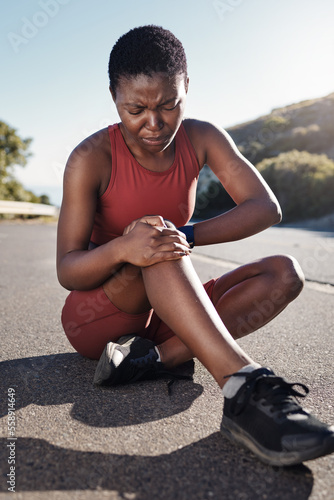 Black woman, knee and sports injury on asphalt in pain from accident, exercise or run in the outdoors. African American woman suffering leg ache holding painful area, joint or bruise during workout