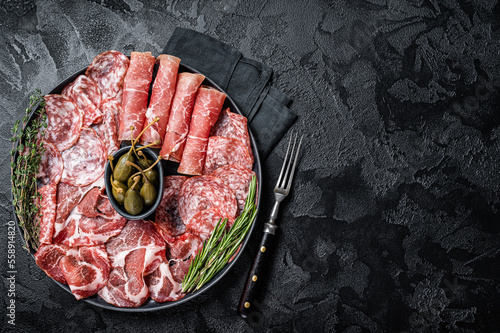 Italian Antipasto set platter, cured meat plate with Prosciutto crudo, Salami and Coppa Sausage. Black background. Top view. Copy space