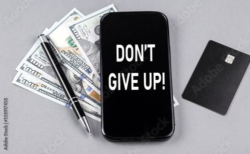 Credit card and text DON T GIVE UP on smartphone with dollars and pen. Business concept
