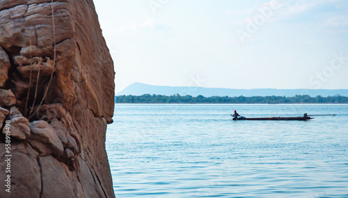 Rocks by the lake, blurred background, fishermen on boats.  Natural scenery that gives a feeling of strength © Supat suttiso