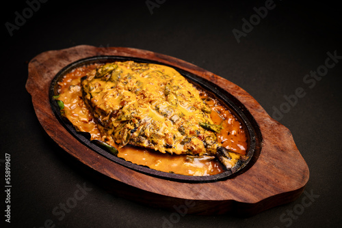 Freshly prepared Thai style whole fish red snapper dinner with tamarind sauce on a white fish shaped plate isolated over a black background. photo