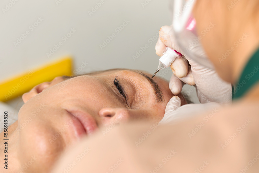 The process of permanent eyebrow makeup in a beauty salon. The permanent tattoo artist