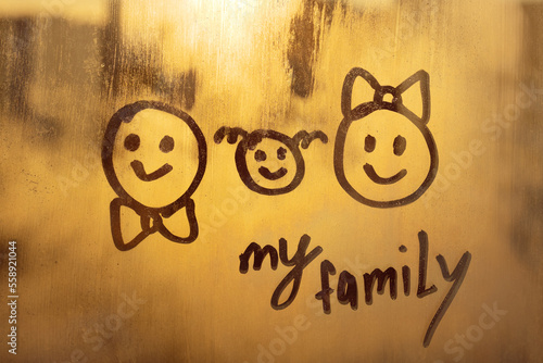 three doodle smile and handwritten lettering text My family on foggy glass sunset window photo