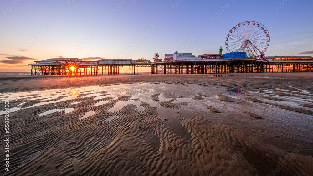 sunset on the beach with pier and wheel