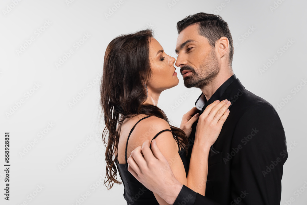 profile of brunette woman in black dress looking at bearded man isolated on gray. profile of brunette woman in black dress looking at bearded man isolated on gray.