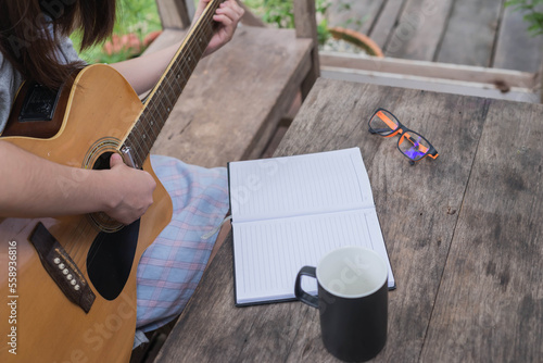 songwriter thinking and writing notes,lyrics in book at studio. playing live acoustic guitar.concept for musician creative.artist composer in work process.people relaxing time with instrument
Photo