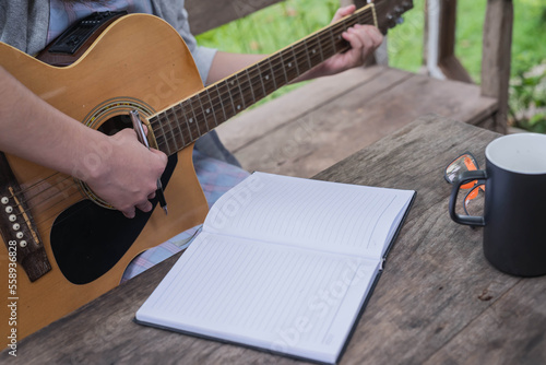 songwriter thinking and writing notes,lyrics in book at studio.man playing live acoustic guitar.concept for musician creative.artist composer in work process.people relaxing time with instrument
Photo