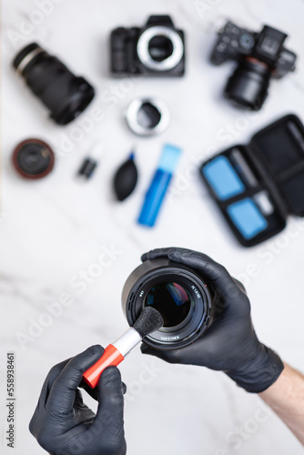 Man hands cleaning camera lens with small brush on cleaning workstation