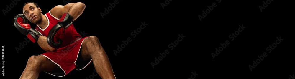 Portrait of man, professional boxer on gloves and uniform training over black background. Combat fighter. Banner Portrait of man, professional boxer on gloves and uniform training over black background. Combat fighter. Banner