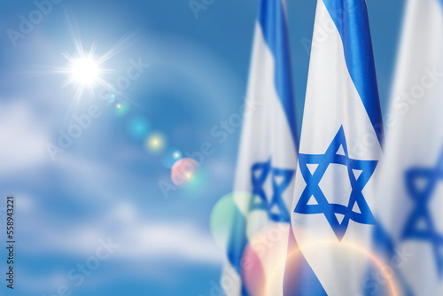 Israel flags with a star of David over cloudy sky background. Patriotic concept about Israel with national state symbols. Banner with place for text. photo