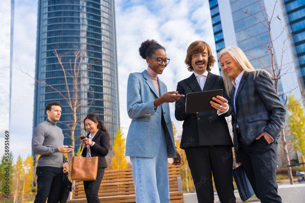 Multi-ethnic business colleagues or executives, looking at technology, glass office buildings Multi-ethnic business colleagues or executives, looking at technology, glass office buildings