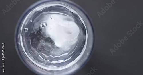 Top view of dropping two effervescent antacid pain reliever tablets to a glass of water